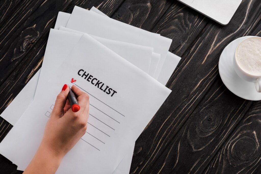 top view of businesswoman holding marker pen near checklist and cup of coffee on table