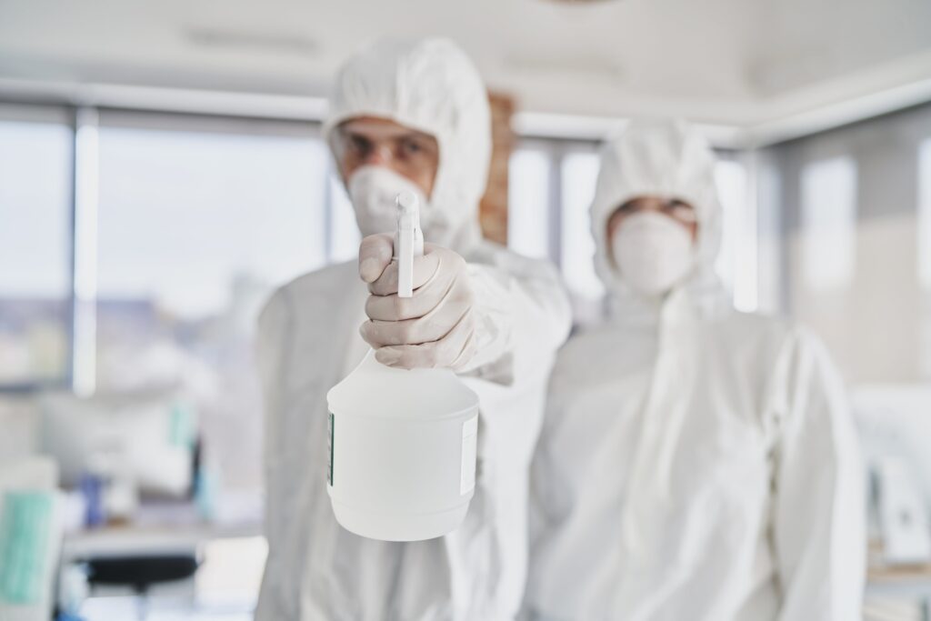 Two technicians holding spray disinfectant in front of the camera 