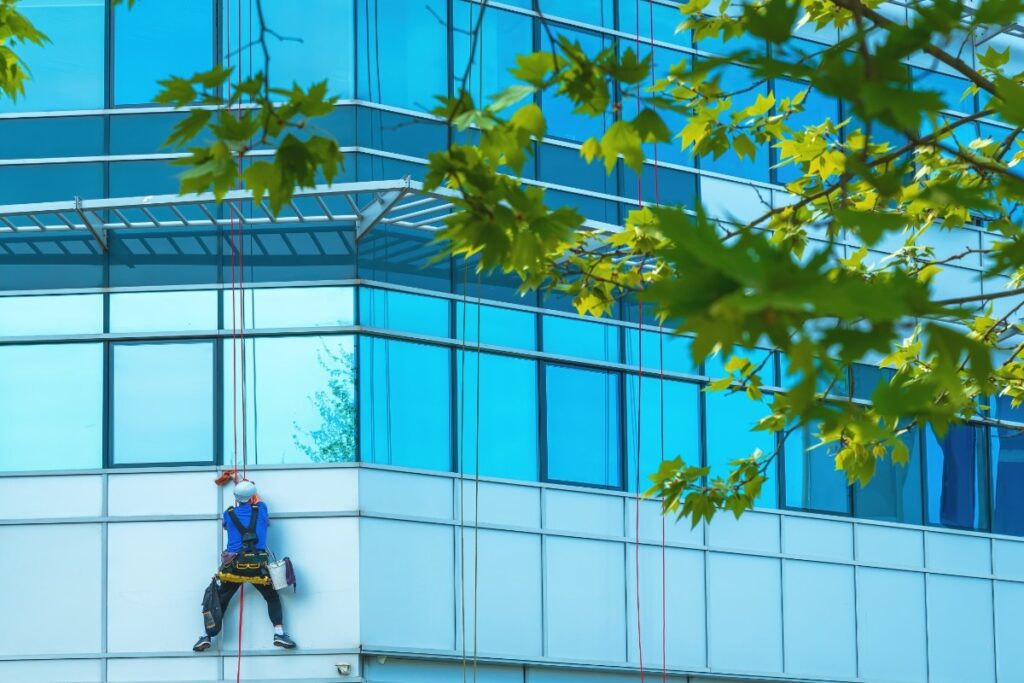Window washer cleaning facade of modern office building
