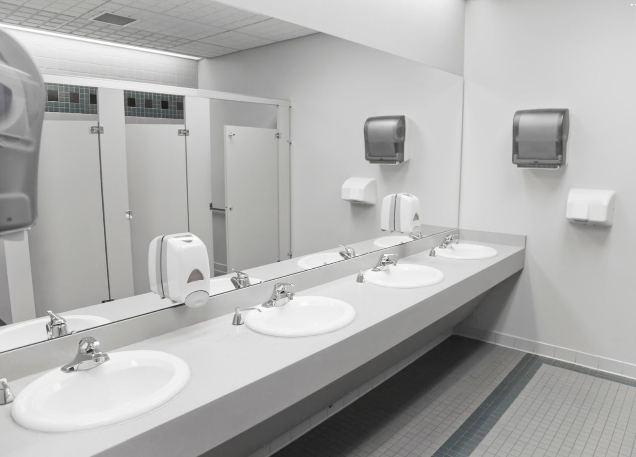 clean commercial bathroom with four sinks and one large mirror