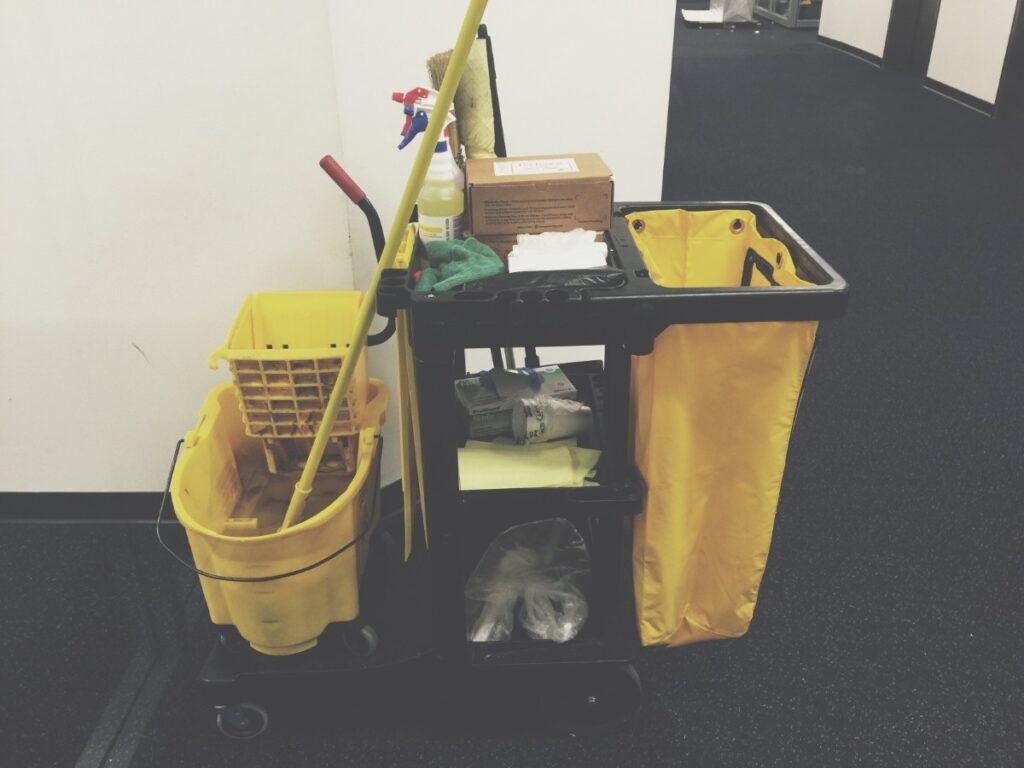 Yellow and black janitorial cart with cleaning accesories