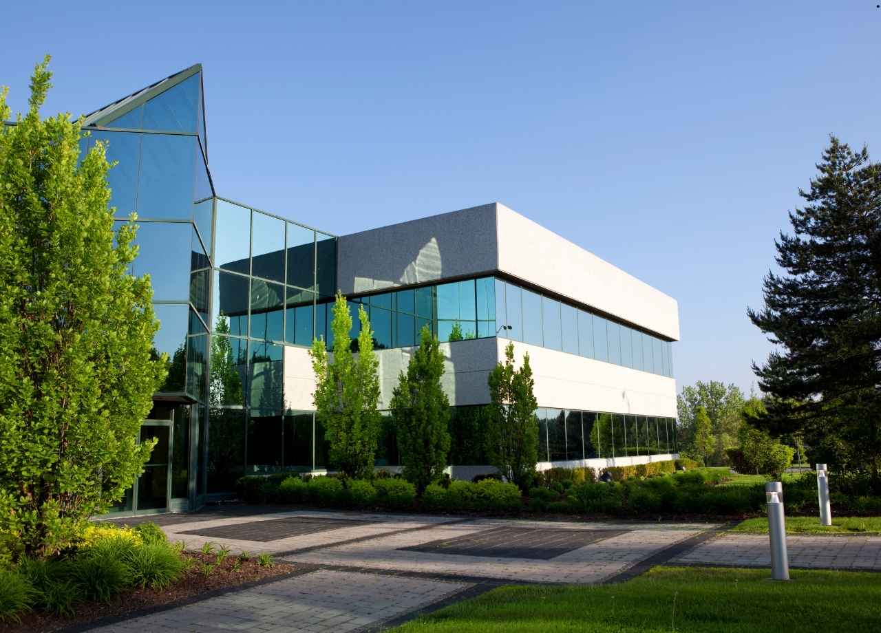 A beautiful commercial buidlding with green grass and tall trees outside