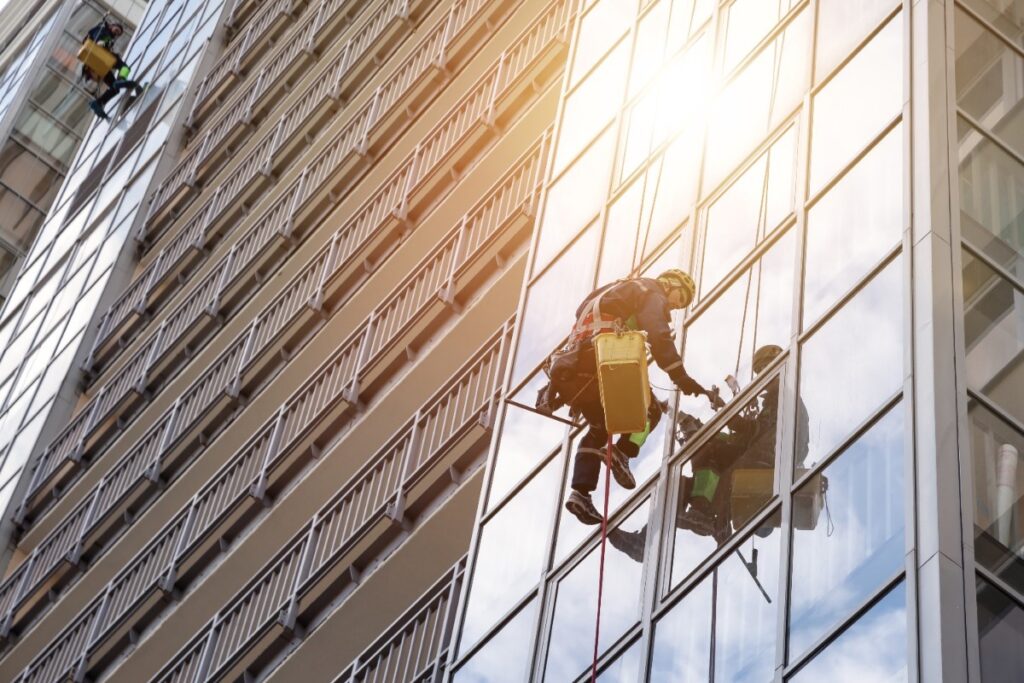 Group Industrial mountaineering workers in uniform hangs over residential facade building