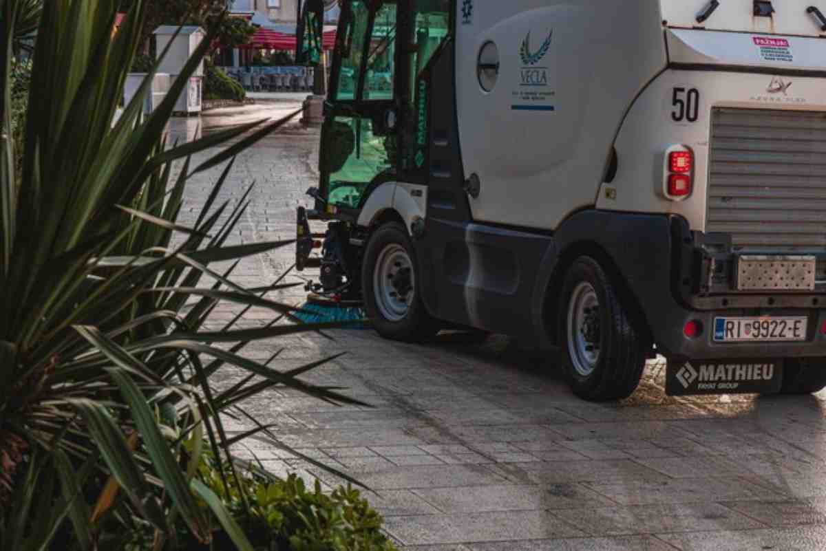 Big parking lot sweeper truck with brushes underneath