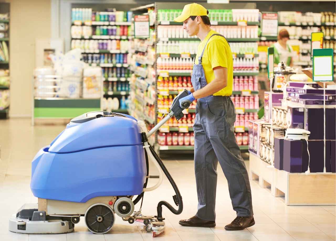 A man in uniform with heavy floor scrubber in a retail store