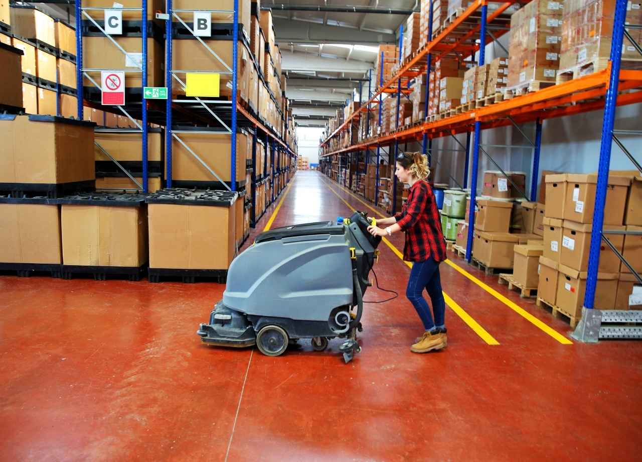 warehouse cleaning by woman with power floor scrubber