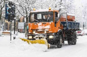 big orange snow truck shoveling truck as its being driven