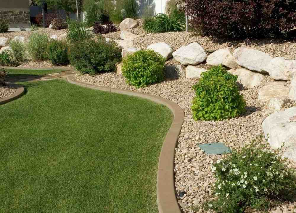 commercial landscaping and hardscaping plants in garden covered in granite stones with grass on the opposite side