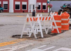 parking lot with potholes and orange and white safety signs