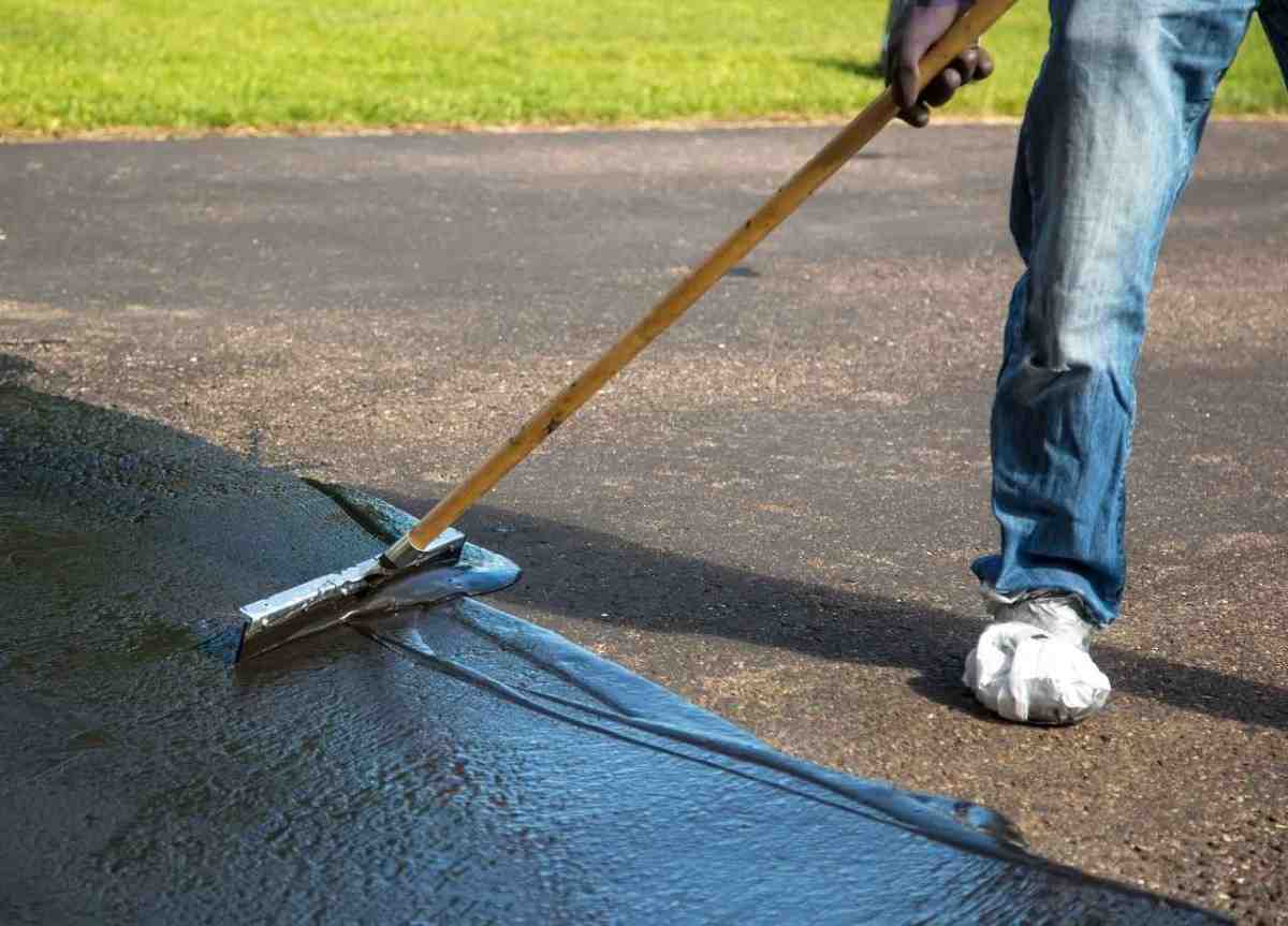 a worker spreading asphalt coating on asphalt