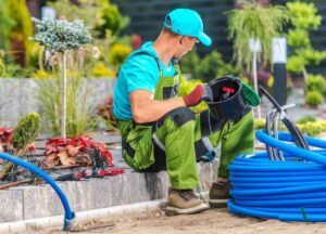 man in overalls sitting and holding blue hose pipe