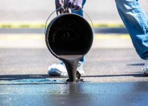 sealcoating being poured on asphalt