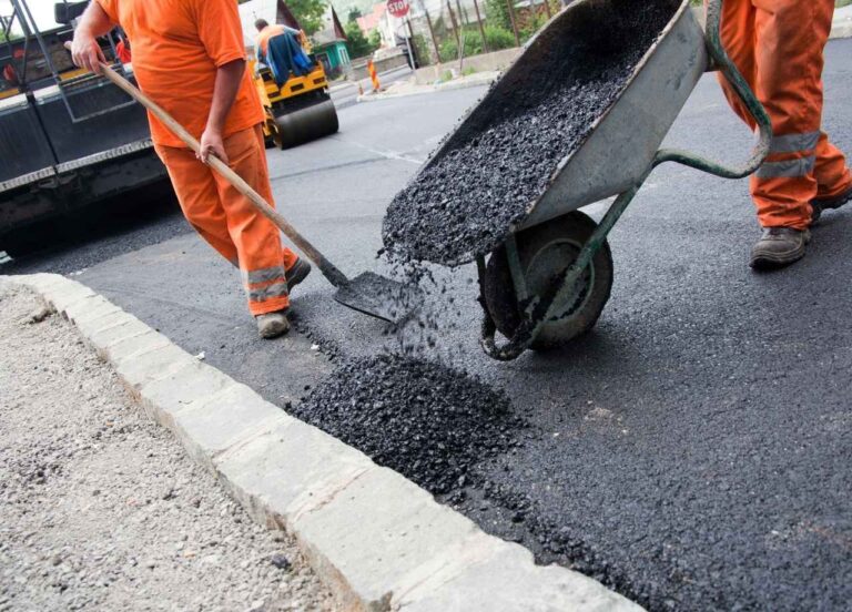 two workers pour asphalt on the sidewalk