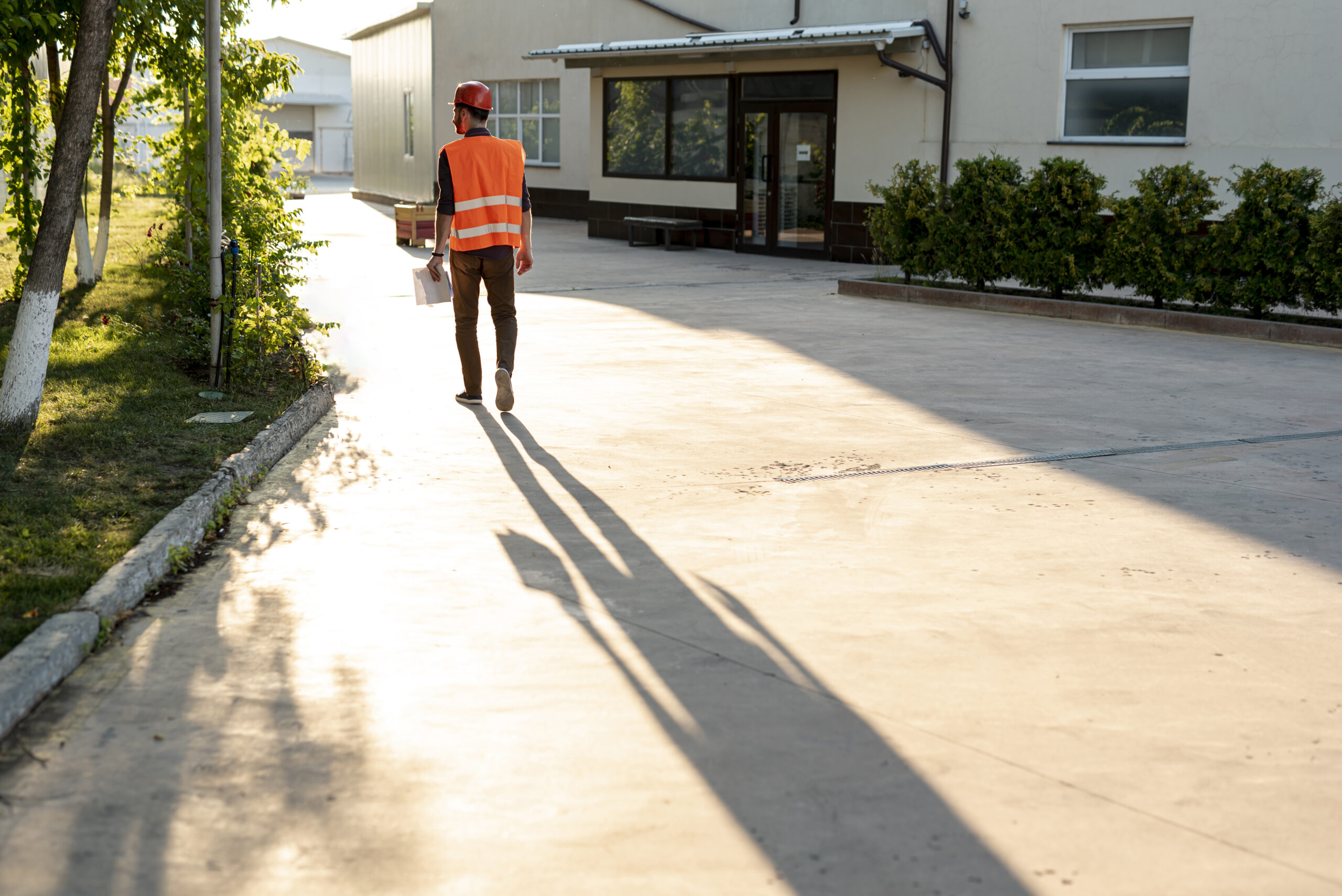 A man wearing orange saftey vest and helment monitoring drainage landscaping 