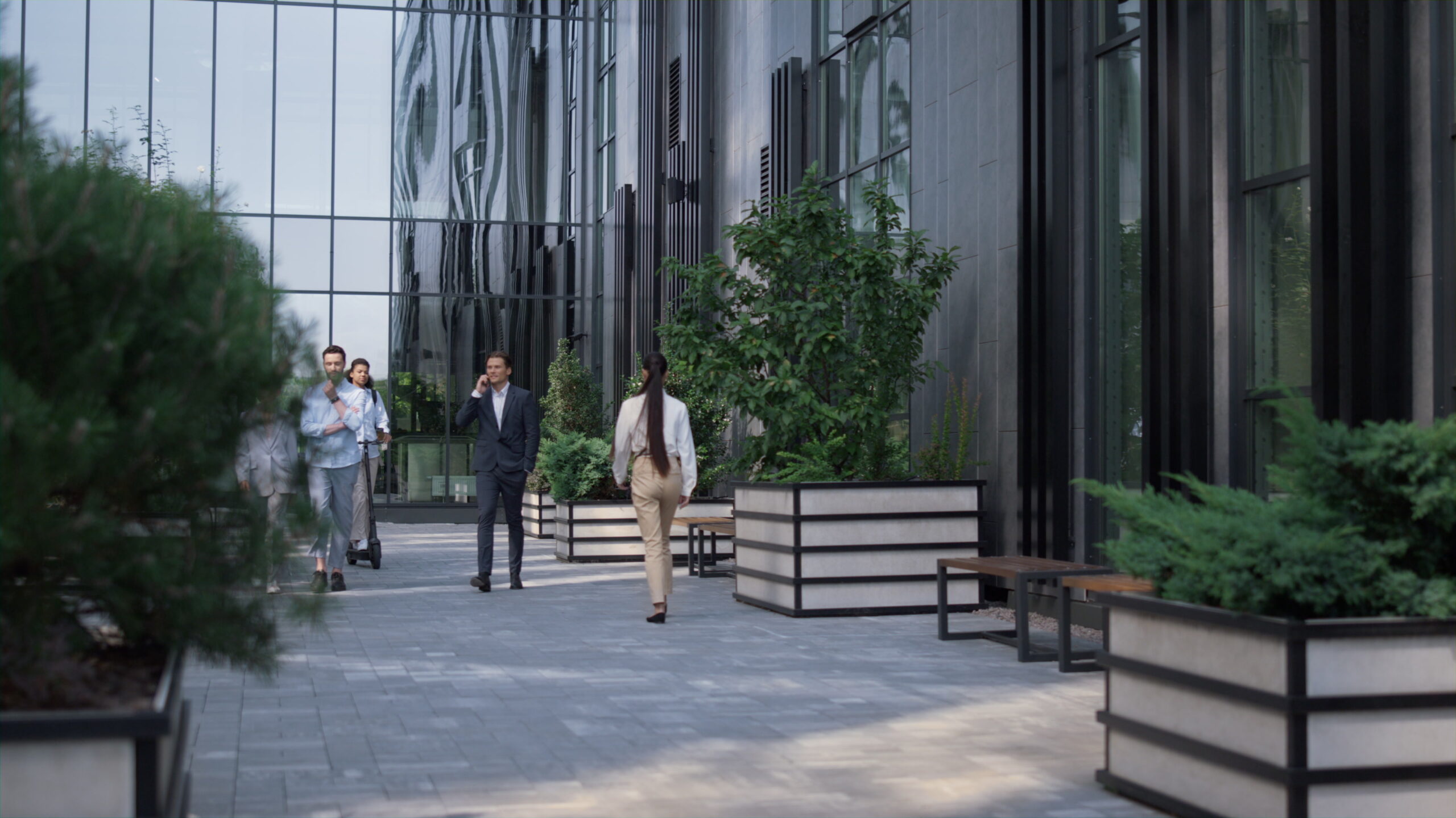 Well landscaped office building with plants and people walking in and out of offices