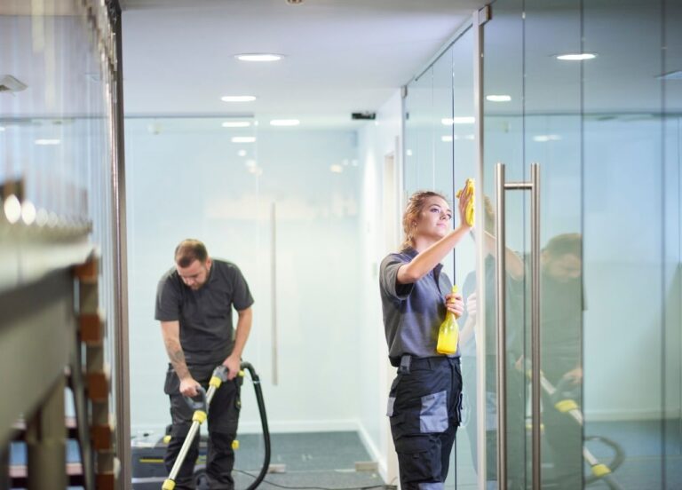 two commercial cleaners cleaning office floor and windows