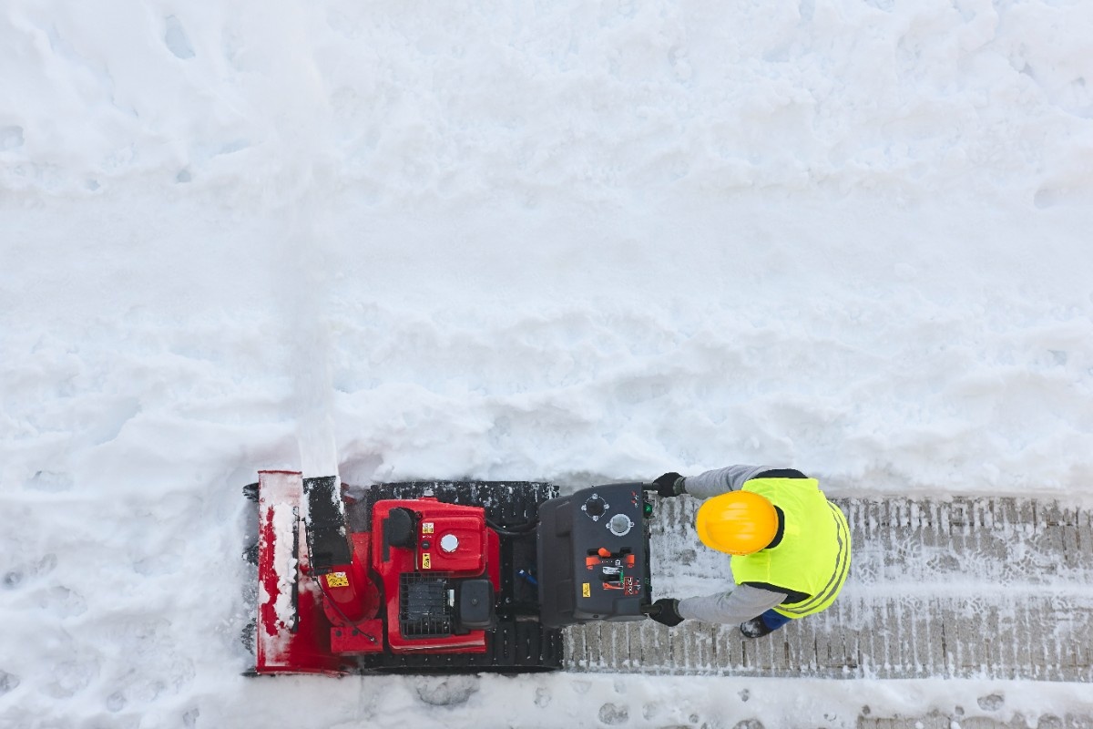 worker-cleaning-snow-on-the-sidewalk-with-a-snowblower