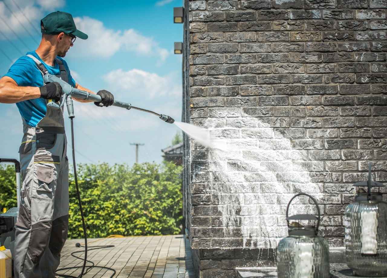 A worker pressure washing a wall