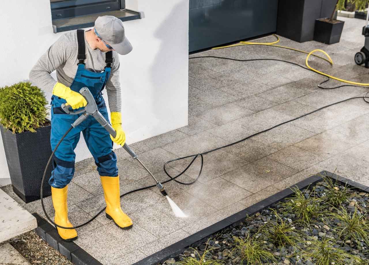 A man pressure washing sidewalk