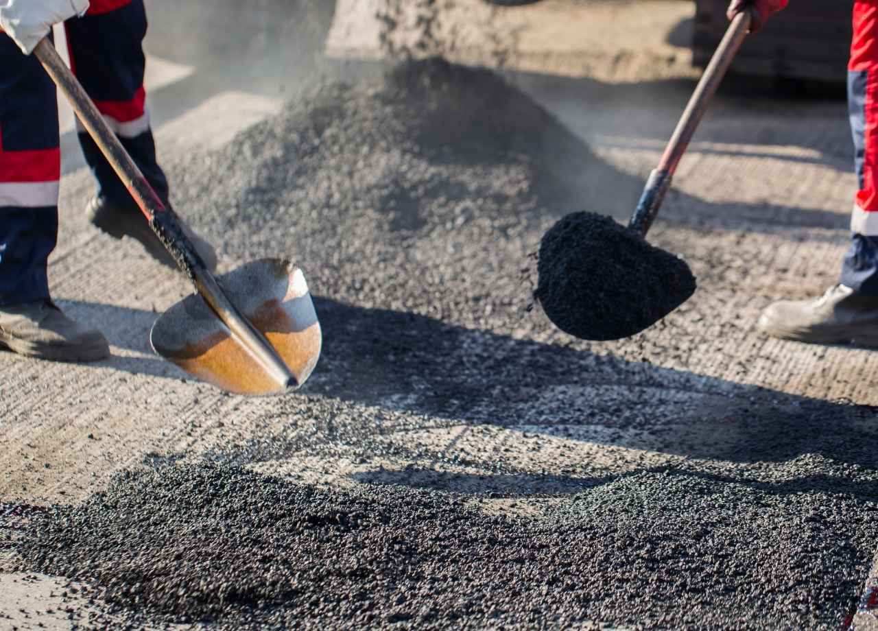 two people shoveling asphalt