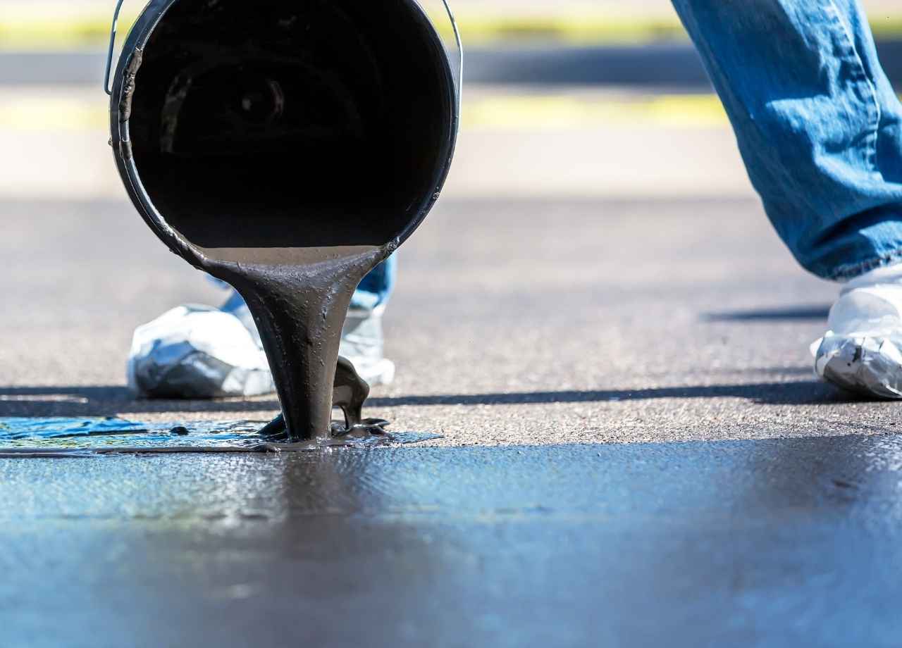 commercial sealcoating being poured onto asphalt