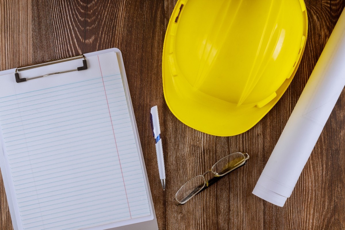 Yellow helmet checklist and pen on a wooden desk