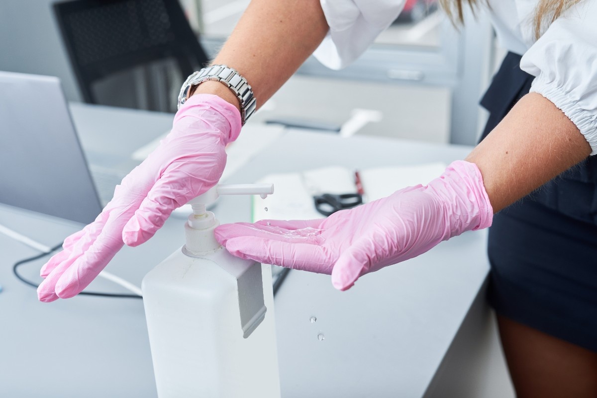 businesswoman-with-face-mask-and-gloves-using-hand-sanitiser