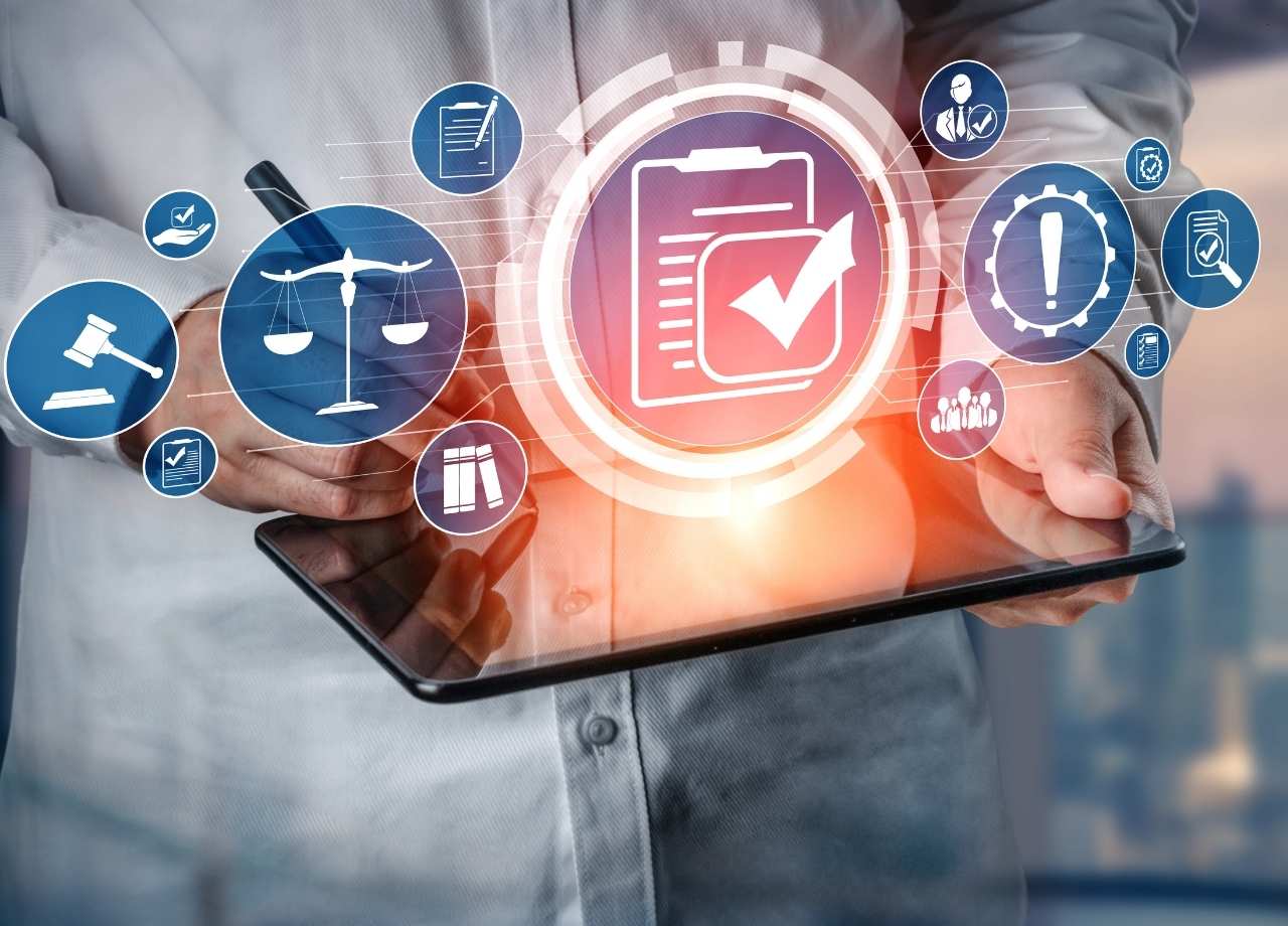 A person holding a tablet doing compliance management with floating icons above tablet