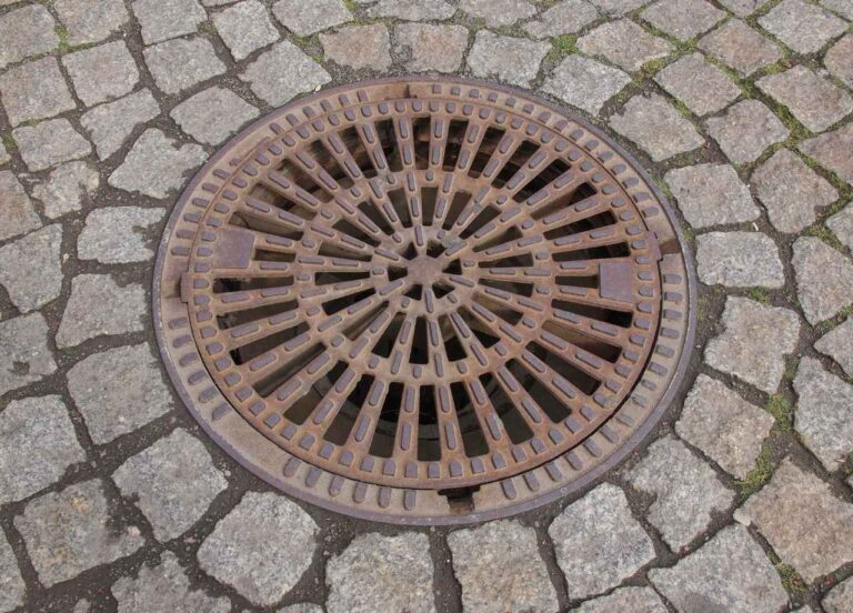 A big drain surrounded by pavement