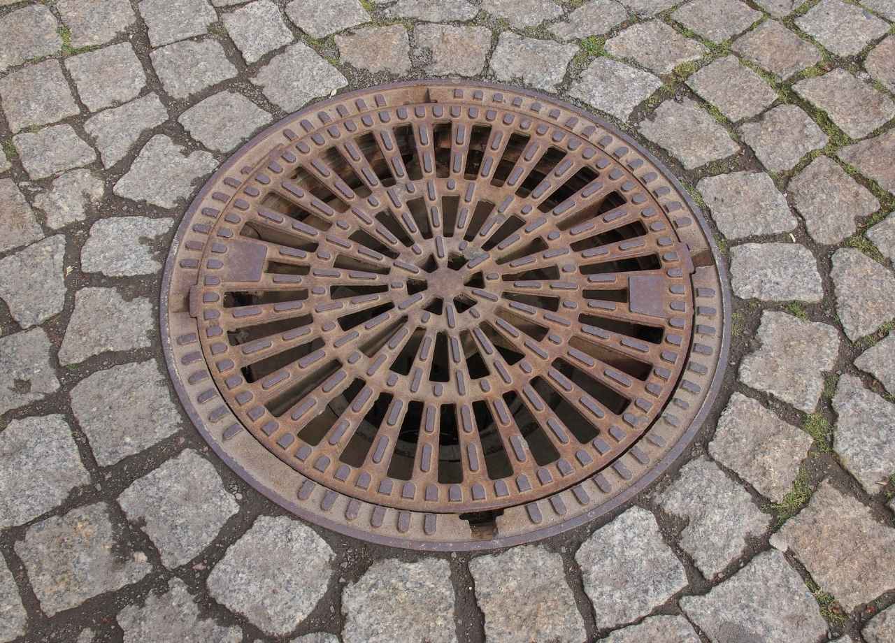 A big drain surrounded by pavement