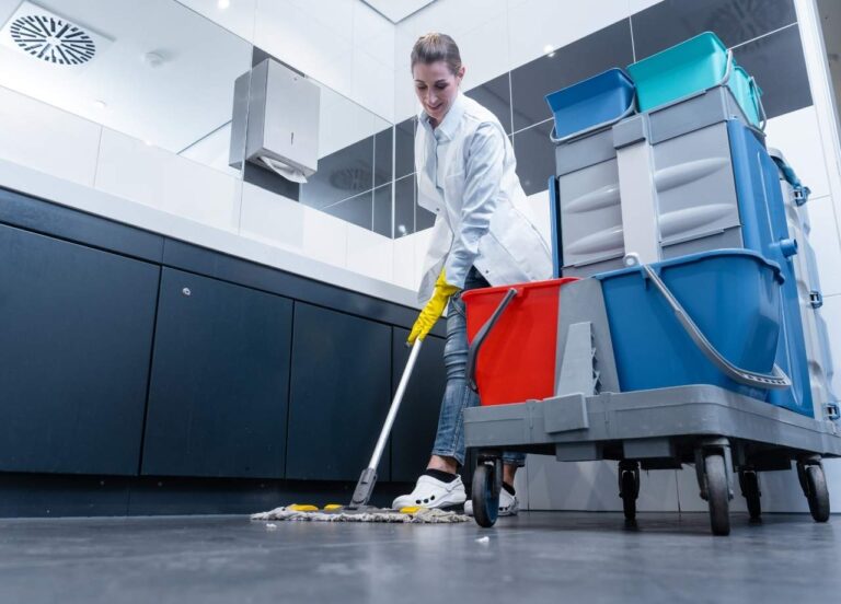 Commercial Restroom being cleaned by worker with a large cart