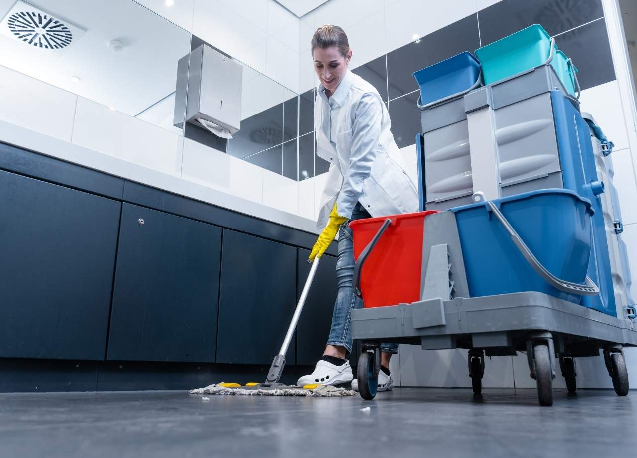 Commercial Restroom being cleaned by worker with a large cart