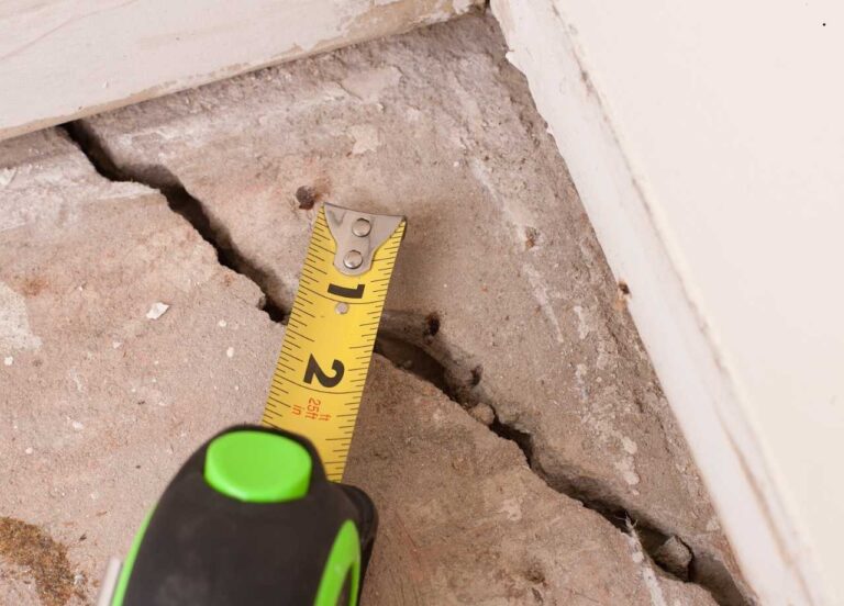 A tape measure measuring a concrete spalling crack