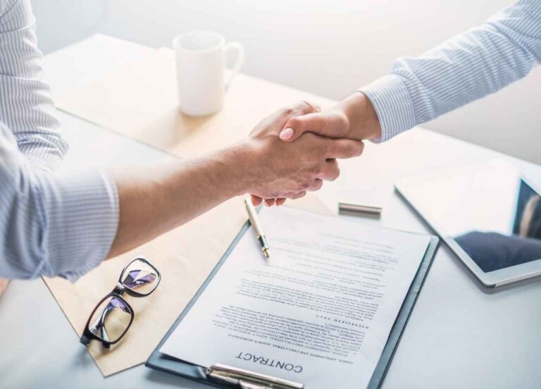 Two people shaking hands over a contract