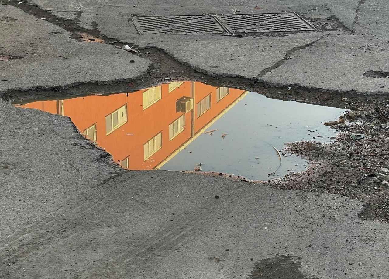 asphalt pothole with big water puddle 