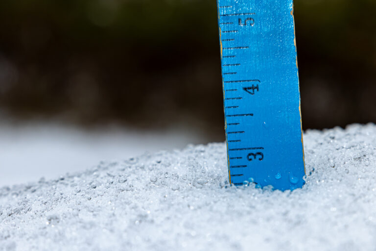 Ruler in snow measuring snowfall depth and ice accumulation from winter snowstorm