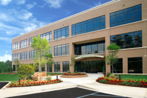 Beautiful seasonal landscaping including flowers and trees decorate the outside of a 3-story office building