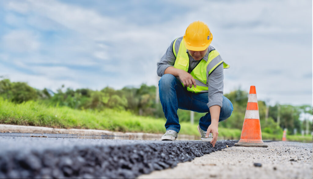 Construction worker reviewing new asphalt layer on commercial site