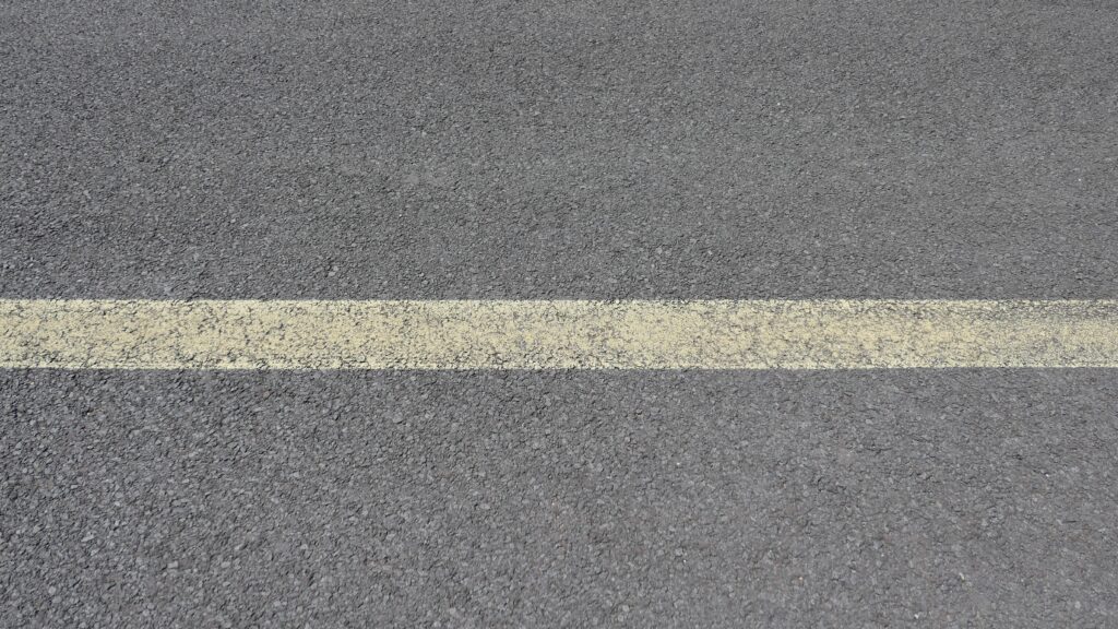 Close Up of Worn Yellow Center Line on Asphalt Road